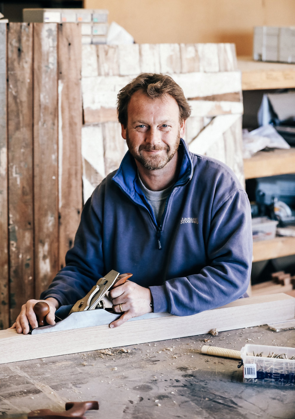 Smiling craftsman in a workshop with a wood plane